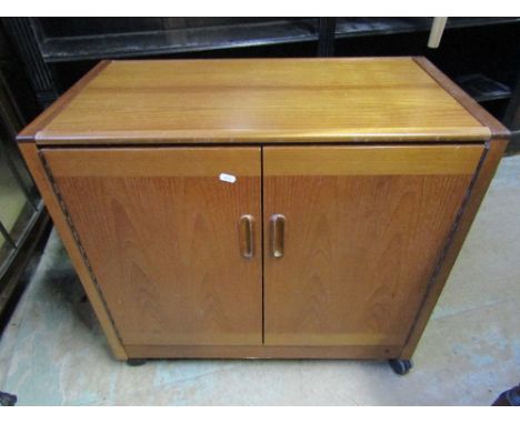 A vintage teak framed hostess trolley enclosed by a pair of rectangular doors beneath a removable top revealing a Philips ele