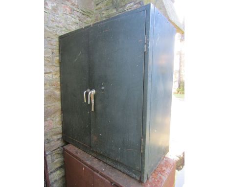 A vintage industrial green painted floor standing steel cabinet enclosed by a pair of rectangular doors with drop bar handles