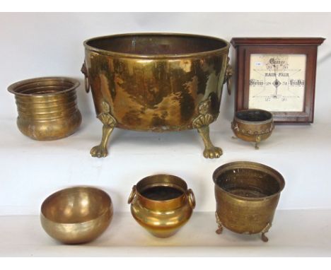 A 19th century brass log bucket, with twin lion head handles and cast paw feet; together with five further brass vessels and 