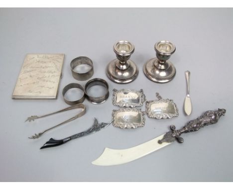 Silver cigarette case, pair of squat candlesticks, two napkin rings, letter knife, three decanter labels, etc, 10 oz weighabl