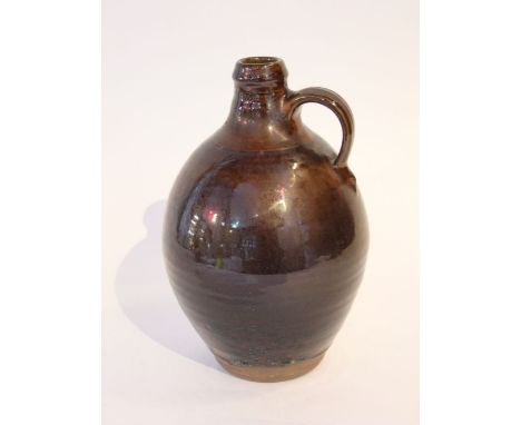 A St Ives pottery flagon with dark glazed finish and single handle to the shoulder, with impressed St Ives pottery mark to ba