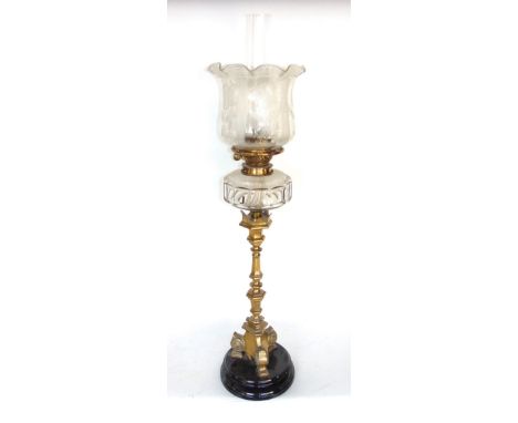 A brass candlestick oil lamp with a faceted glass reservoir and polished circular slate plinth base, 75 cm high