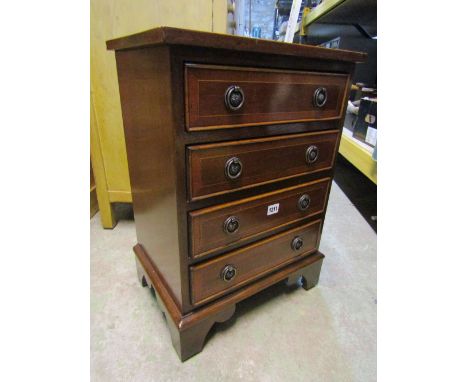 A miniature Georgian style mahogany chest of four long drawers with cross banded detail on bracket supports, 45cm wide