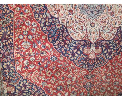 An eastern style wool carpet, the central medallion upon a red field with multi floral detail within multi running borders, 2