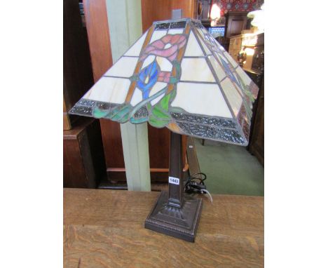 A contemporary Tiffany style table lamp with square tapered coloured leaded light shade and raised on an inverted cast column