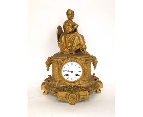 French gilt metal figural two train mantle clock, mounted by a seated lady holding a bird, fitted with an 8cm enamelled two t