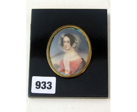 A portrait miniature of oval form showing a bust length portrait of a lady in 19th century style costume including a lace bon