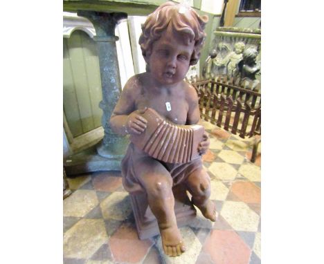 A 19th century cherub with terracotta finish, seated and playing an accordion, 75cm tall 