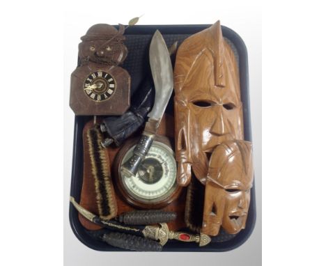 A Kukri knife in sheath, Black Forest style cuckoo clock, carved wooden masks, oak barometer on shield with two brushes etc 