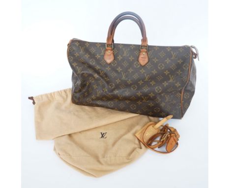 LOUIS VUITTON: A MONOGRAM LEATHER BAGThe brown monogram bag with tan leather detailing and gold hardware, with two luggage ta