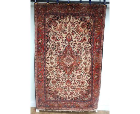 KASHAN RUG, PERSIANThe ivory field with a madder pole medallion, dark and light indigo spandrels all with abundantly floral s