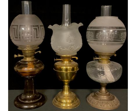 An early 20th century oil lamp, smoky glass font and pedestal base, Greek key frosted glass shade; a Victorian style oil lamp