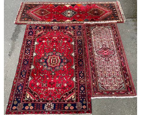 A Middle Eastern rug or carpet, central medallion within a field of stylised flowers and geometric motifs, in shades of red, 