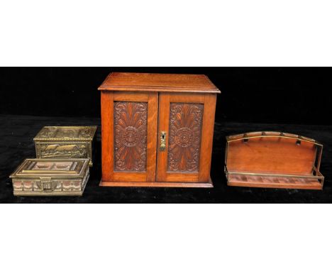 An Edwardian oak smoker's cabinet, moulded top, pair of fielded carved doors, brass escutcheon, fitted with an arrangement of