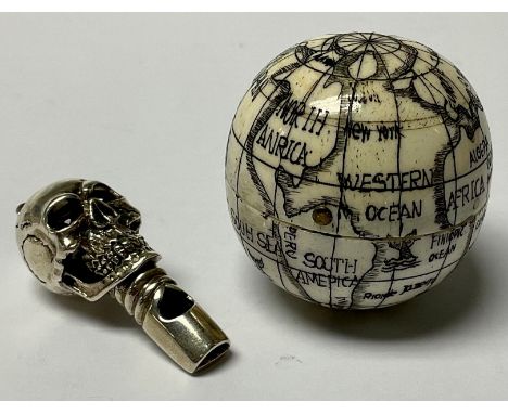 A sterling silver macabre skull whistle, set with red stone eyes, suspension loop, marked 925, 4.5cm, 17g; a resin reproducti