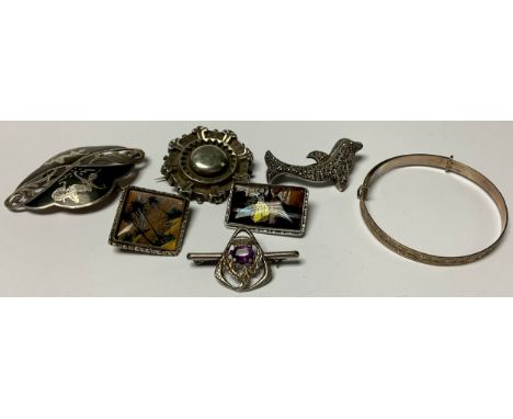 A Siam silver brooch, a silver marcasite dolphin brooch; a silver target brooch; a silver and amethyst thistle brooch; a silv