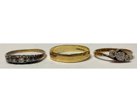 An 18ct gold wedding band, size R, marked 750, 2.4g; two 18ct gold illusion set diamond rings, 4.5g (3) 