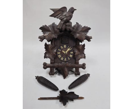 Carved Black Forest wood striking cuckoo clock, early 20th century, surmounted with a bird on leafy branches, with simulated 