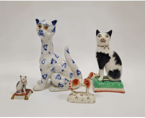 Late 19th century Staffordshire pottery model&nbsp;of a black and white cat seated on a green cushion, 18.5cm high, a Staffor