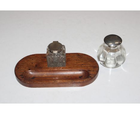 A square cut glass and silver mounted inkwell on wooden desk stand and another glass silver topped inkwell