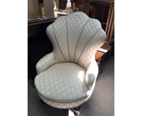 An Art Deco design cream fabric upholstered chair with turned legs terminating in brass caster