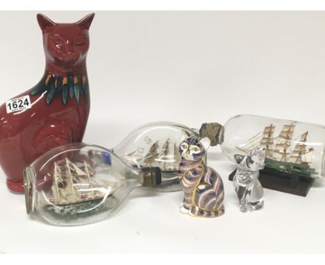 A large Poole pottery cat a Royal Crown Derby cat a Crystal glass cat and three ship in bottles ornaments. (6)