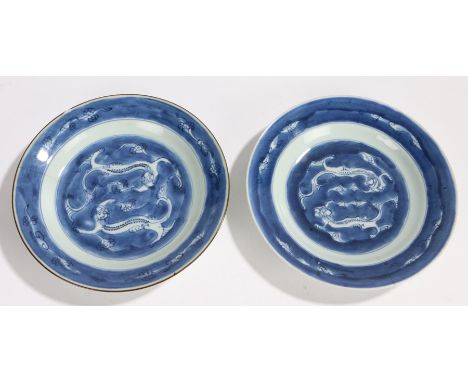 Two Chinese porcelain plates, Kangxi, with blue and white dual dragon decoration with cloud surround, one with a stylised cha