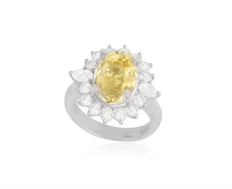 A YELLOW SAPPHIRE AND DIAMOND DRESS RINGOf cluster-design, centring an oval-shaped yellow sapphire weighing approximately 7.9
