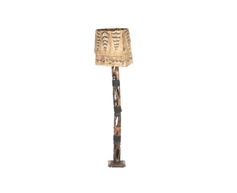 A carved wood standard lamp. Carved on commission in Zambia with pierced panels of figures and huts, with a hand painted shad
