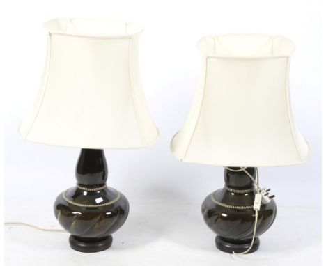 A pair of mid-century ceramic Chinese style table lamps. Glazed in dark brown, on turned wooden bases, with cream fabric shad