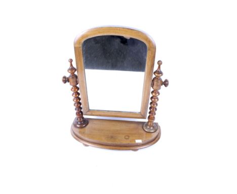 An Edwardian mahogany dressing swing table mirror. With bobbin turned columns having a semi-circular base, raised on bun feet