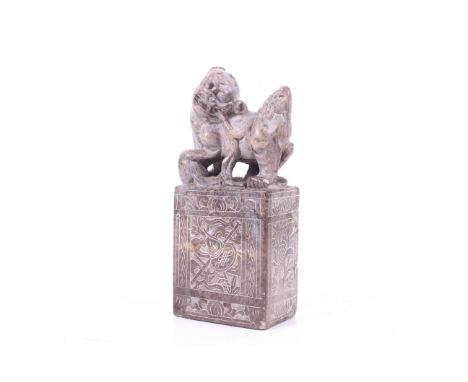 A 20th century Chinese soapstone seal. The mottled beige stone carved with a Fo dog playing with a brocade ball to the top, t