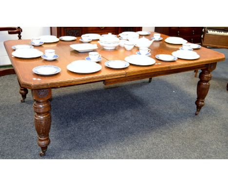 A Victorian oak wind out dining table canted rectangular top turned and reeded legs, ceramic casters (one leaf), c.1860