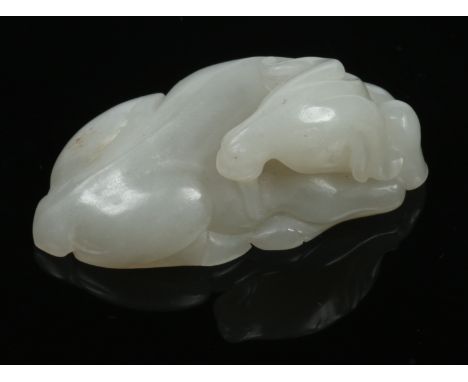 A late 19th century Chinese celadon jade model of a recumbent goat. Carved with its head turned to the rear and one hoof slig