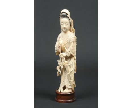 A Japanese Meiji period carved ivory okimono. Formed as a female samurai with a sheathed sword by her side, holding an arrow 