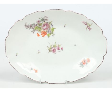 A Chelsea scalloped oval dish. The rim edged in brown enamel and painted in coloured enamels with a loosed bouquet and scatte