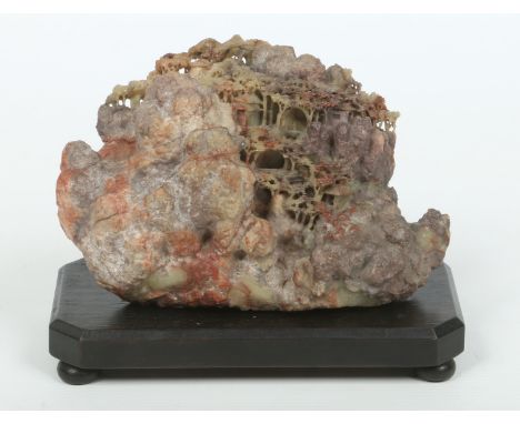 A Chinese carved soapstone boulder on ebonized plinth. Depicting a mountain village scene with small pagoda huts and pine tre
