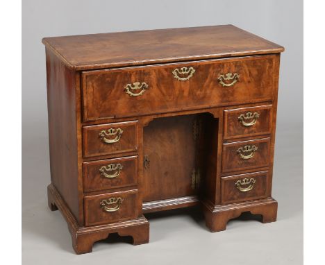 A George II figured walnut kneehole writing desk. Quarter veneered, with feather and cross banding, having oak drawer linings