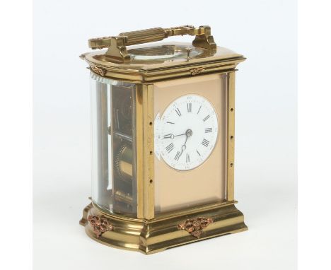 A brass bow sided carriage clock with platform escapement and repeating mechanism striking on a gong. With gilt mask and enam