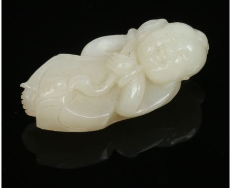 A late 19th century Chinese celadon jade pendant. Carved in the form of a child holding a ruyi sceptre and with russet inclus