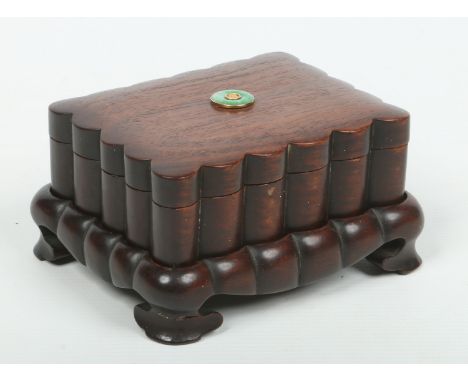 An early 20th century Chinese carved hardwood box, cover and stand of fluted form. Set to the cover with a yellow metal round