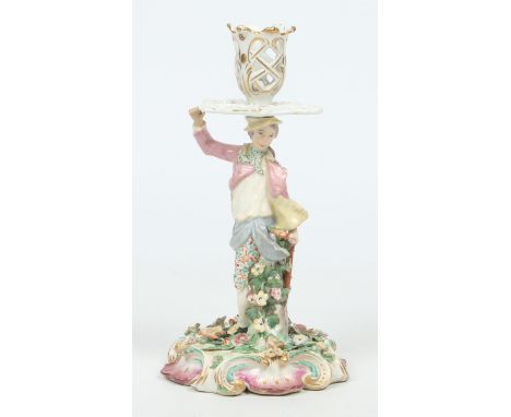 A Chelsea figural candlestick formed as a gardener. With open lattice work sconce and drip tray supported upon the figures to
