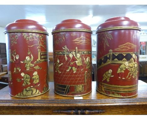 A set of three red chinoiserie tea canisters and covers