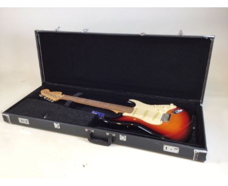 Electric guitar in hard carry case. A Squier Stratocastor by Fender. Plate to back engraved with 20th Anniversary