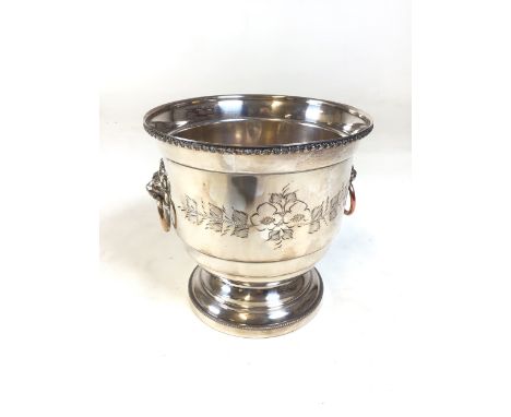 Silver plate wine bottle ice bucket, with decorative relief insert. Drop handles over lion masque backplates. Fascia with eng