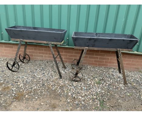 A pair of wooden drop in trough planters on metal stands with wheels. W:100cm x D:30cm x H:80cm