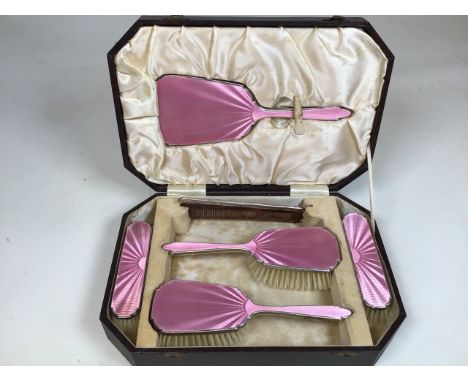 A boxed pink enamel silver backed dressing table set. Comprising hand mirror, a pair of hand brushes and two clothes brushes 