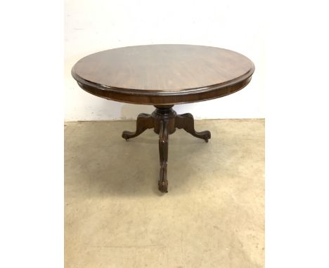 A circular breakfast tilt top table on turned column and tripod base with metal castors. W:104cm x D:104cm x H:72cm