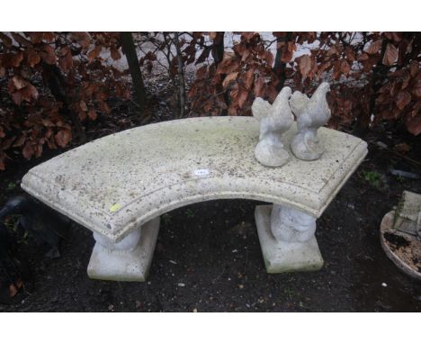 A concrete garden bench raised on squirrel decorated plinths and two concrete dove ornaments