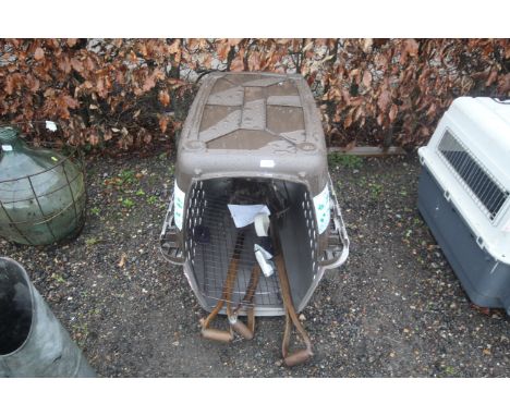 A large plastic pet crate and a small quantity of wooden handled garden tools